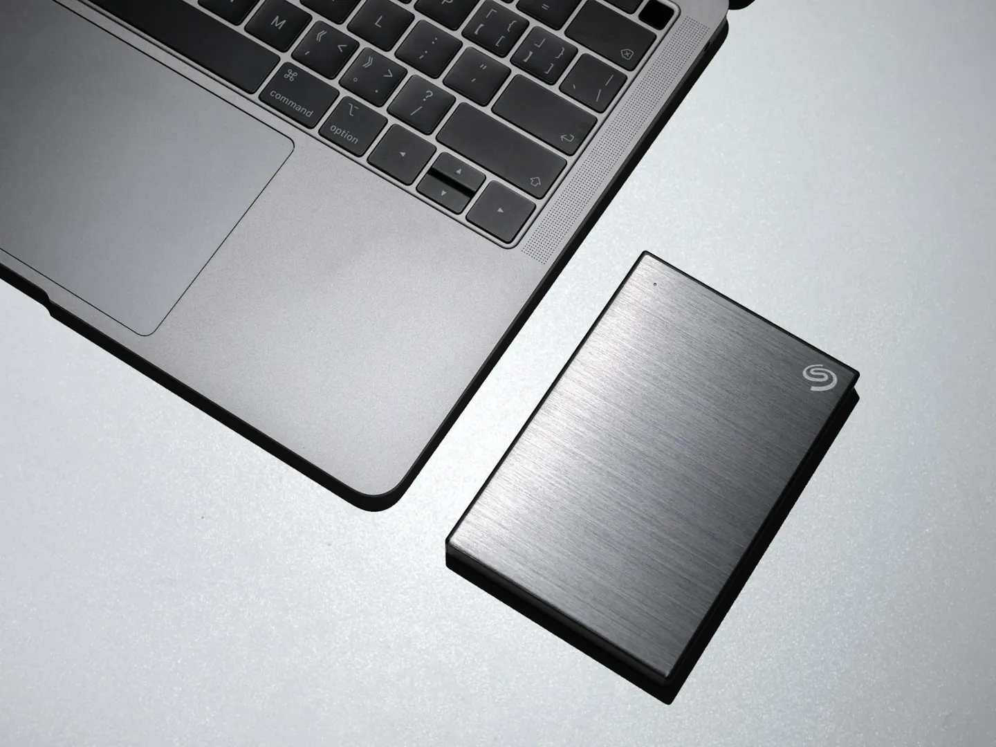 A laptop beside an external backup drive