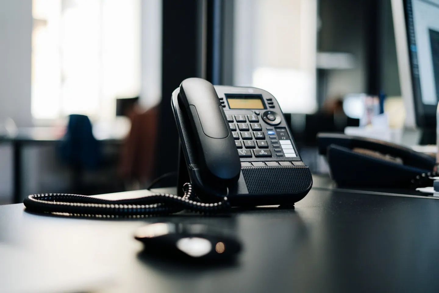 An office desk phone beside a computer mouse