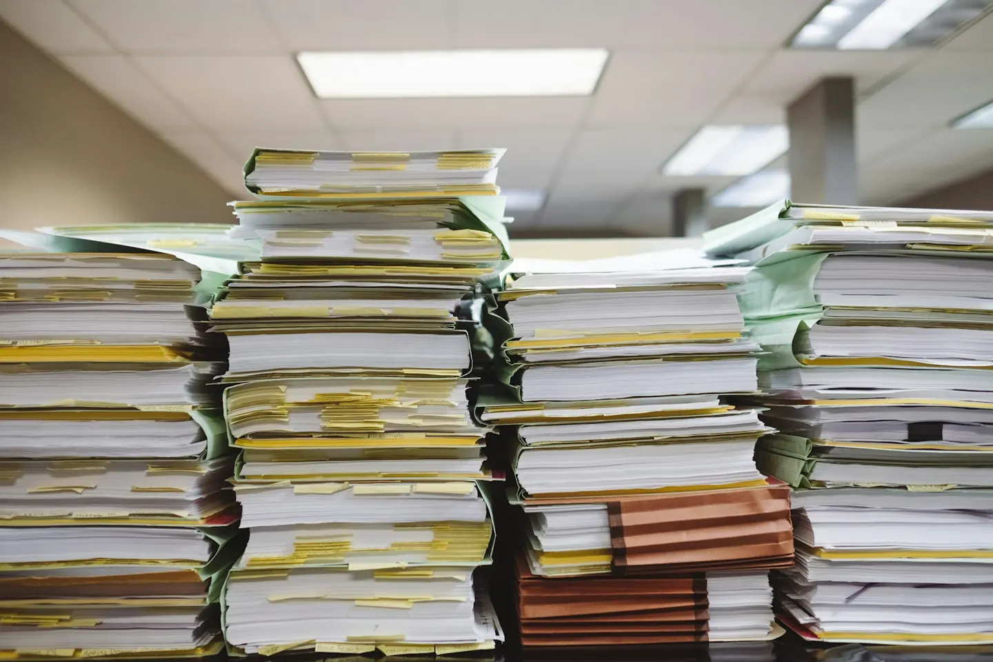 Tall stacks of paper files on office desks