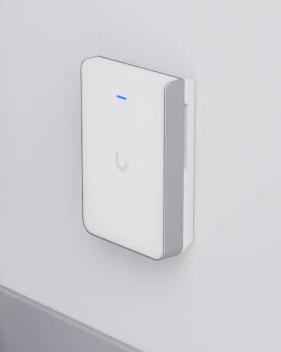 A UniFi in-wall access point mounted beside a doorway